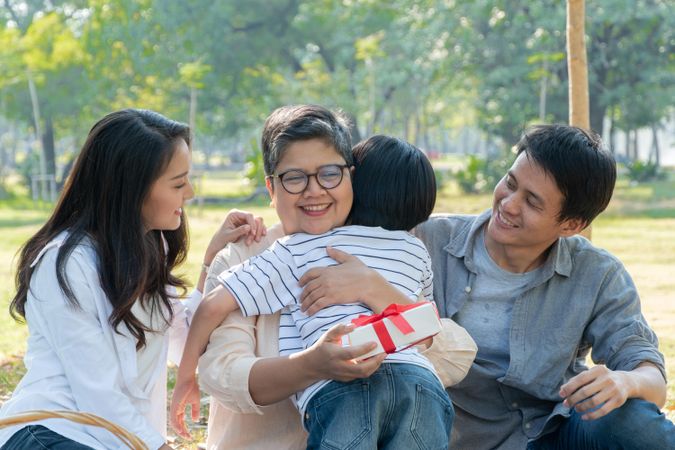 Family celebrating grandmother’s birthday with a picnic in a public park