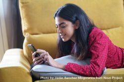Woman relaxing at home while reading on a smart phone 4dN8n0