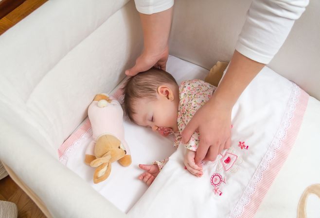 Hands of mother looking after her baby girl sleeping
