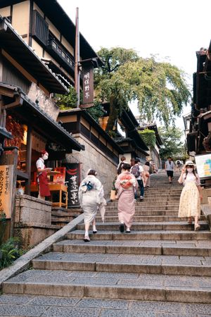 Back view of woman in kimonos climbing an outdoor stairs