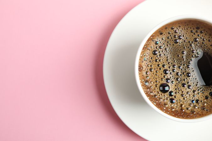 Cup of coffee on color background, space for text
