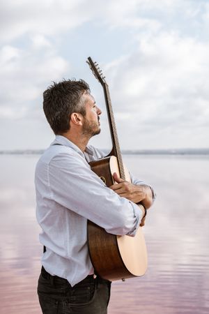 Inspired musician embracing guitar at seaside