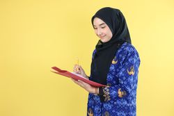 Young Worker Wearing Korpri Batik Uniform Holding Pencil, Checking Document Paper