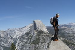 Attentive tourist with backpack standing on mountain peak