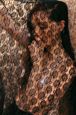 Portrait of woman with face under textured dark lace