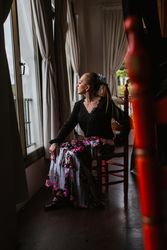 Woman dancer in suit for flamenco sitting and looking out window