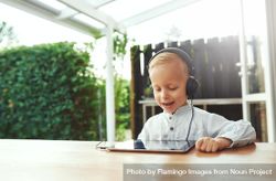 Happy blond boy using headphones listening to something on digital tablet, copy space 5RvnO5