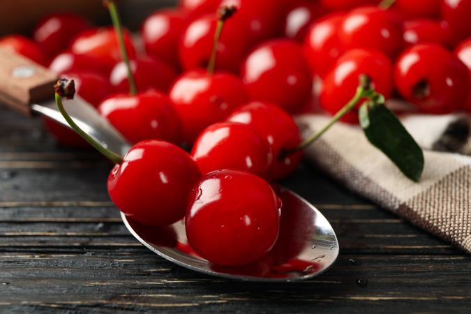 Towel and spoon with cherry on wooden background, close up