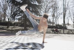 Shirtless man dancing break dance in park
