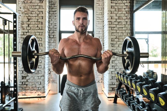 Bearded man exercising with barbell in gym