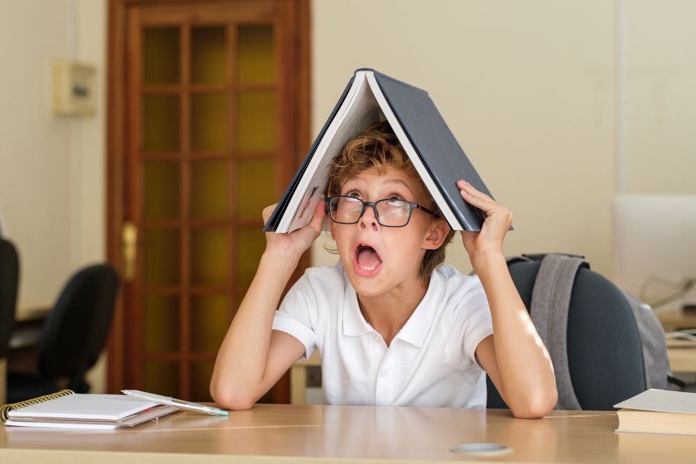 Comic schoolboy with book on head