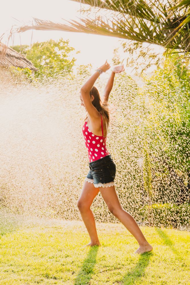 Cheerful teenager having fun with jet of water