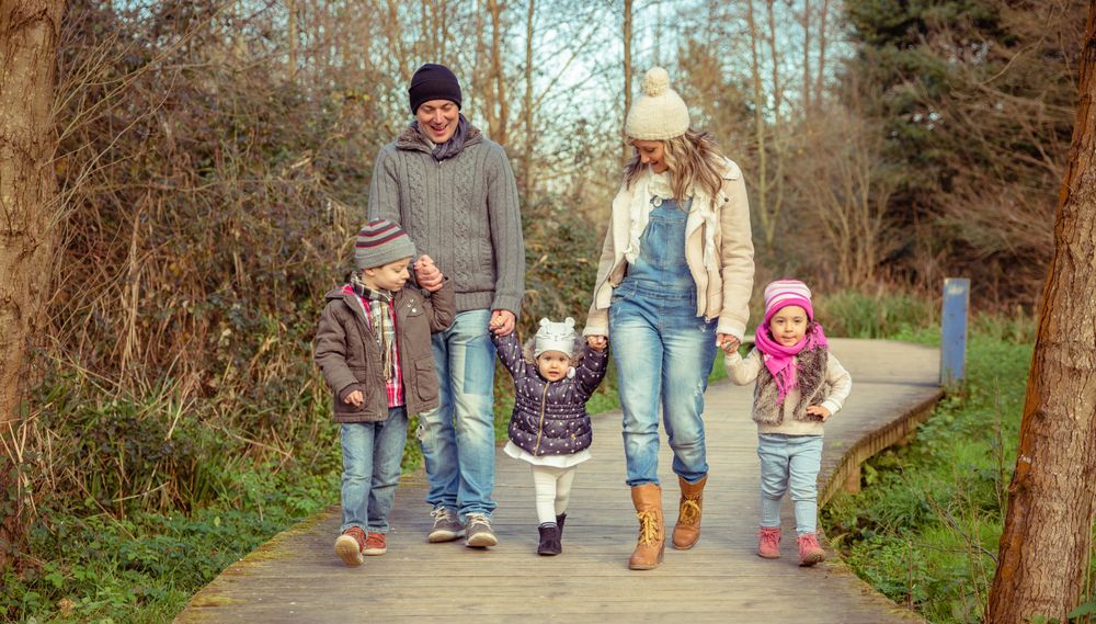 Happy family of five walking along path in forest