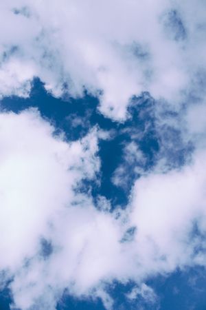 Vertical composition of fluffy clouds in blue sky