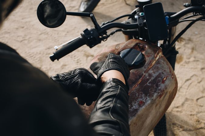 Person wearing leather sitting on motorcycle with phone