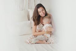 Mother ticking little son and laughing on bed