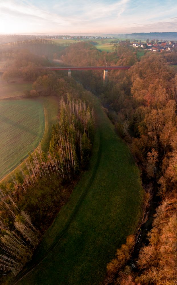 Sunrise drone panorama with bridge crossing river surrounded by nature