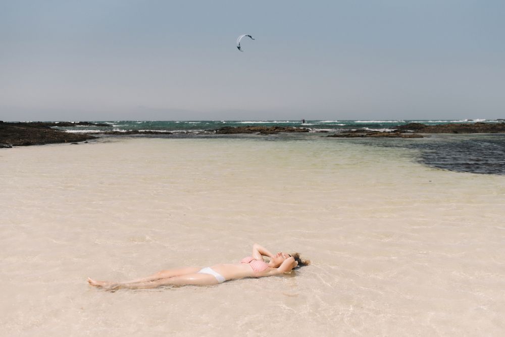 Woman in swimsuit lying in water on seashore