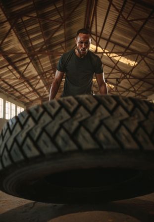 Muscular man doing cross training inside old warehouse