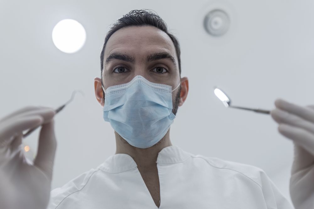POV of dental patient looking up at dentist leaned over chair at clinic
