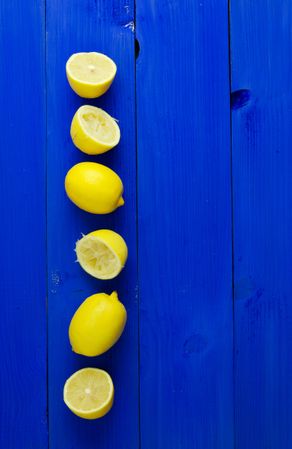 Cut and whole lemons stacked on the left on wood painted blue