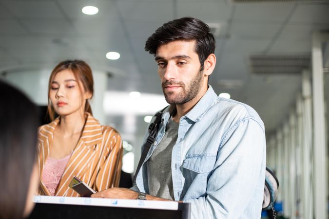 White man and Asian woman checking in for flight at airport