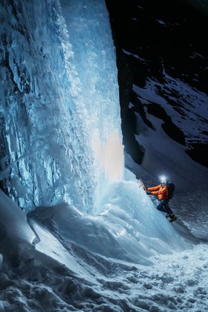 Confident climber with flashlight climbing glacier at night