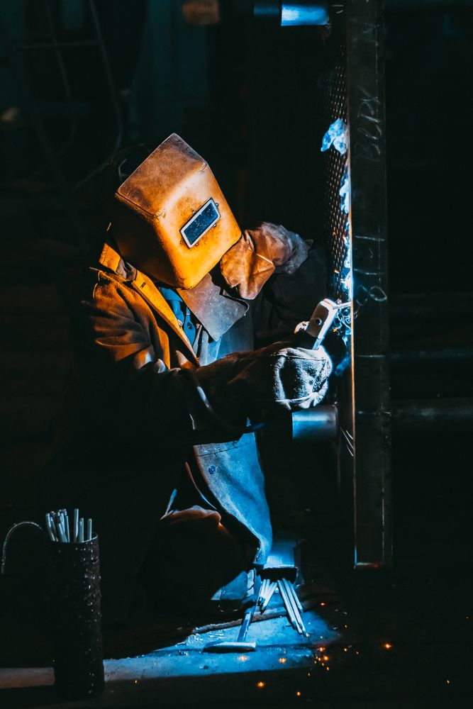 Man in red welding helmet in a dark room