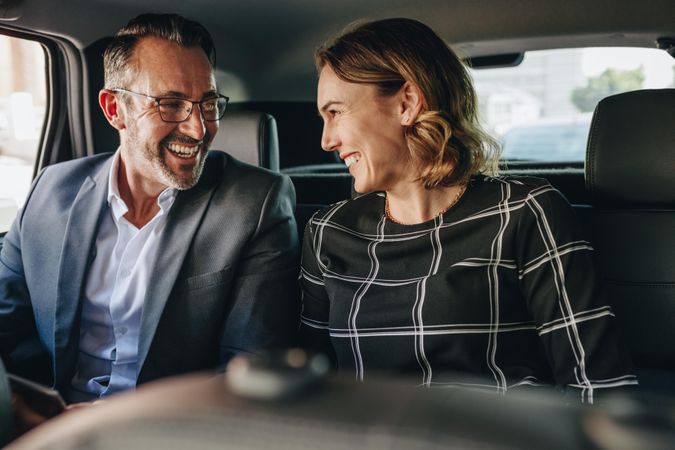 Two business people traveling in backseat of a car