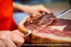Close up of woman’s hands in butcher shop slicing meat beJ860