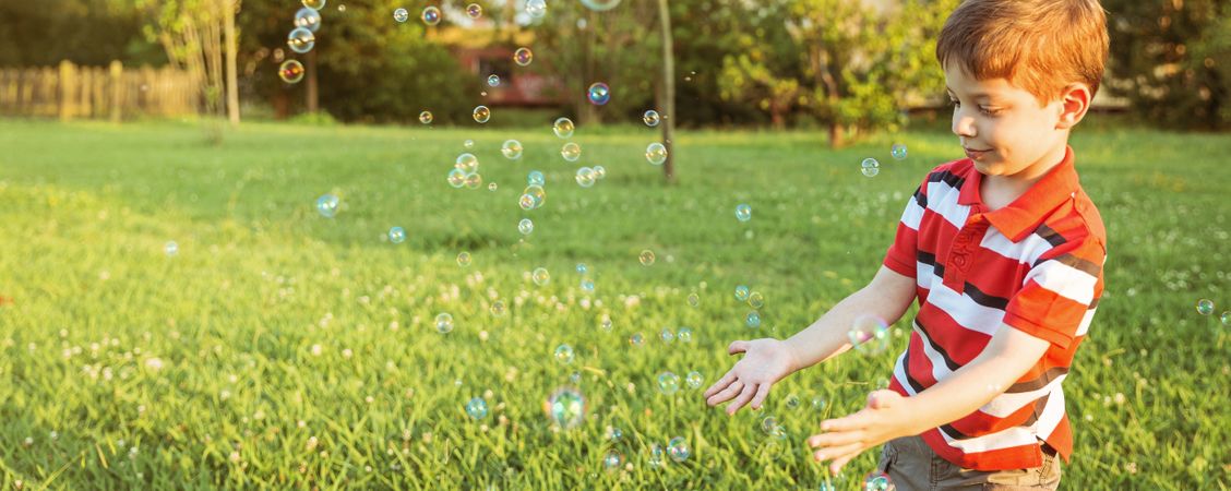 Happy boy playing with soap bubbles in the park