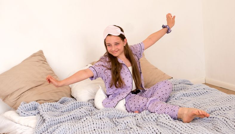 Girl yawning while stretching on bed