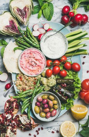 Fresh tray of snacks of fresh vegetables, olives, hummus, and dolmas