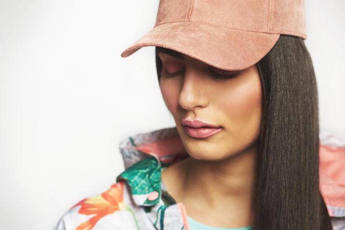 Beautiful woman pictured in colorful printed floral hoodie with her eyes closed wearing a cap