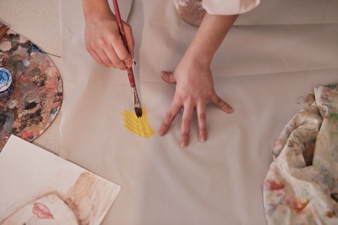 Crop woman painting with brush