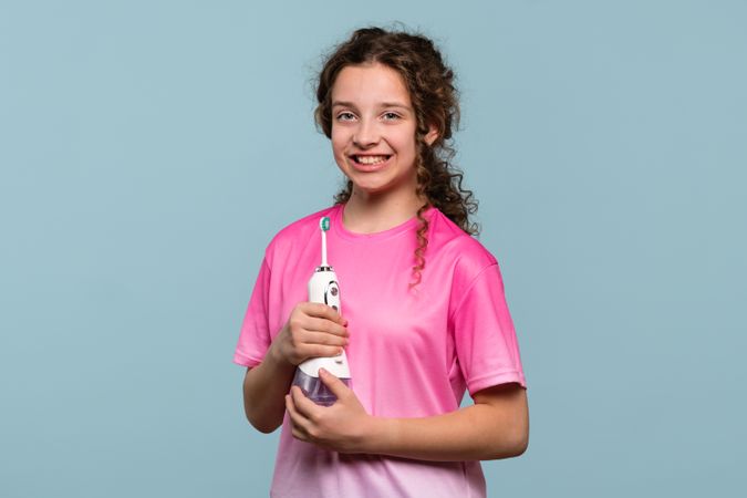 Smiling girl with an electric toothbrush