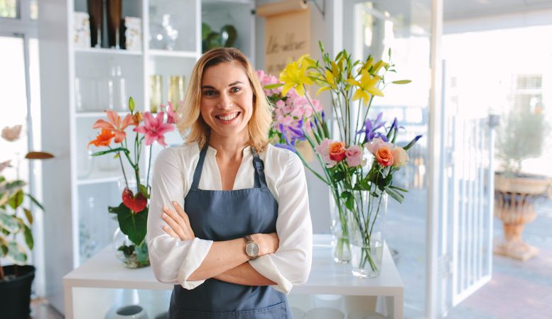 Beautiful and happy young woman florist standing in flower shop
