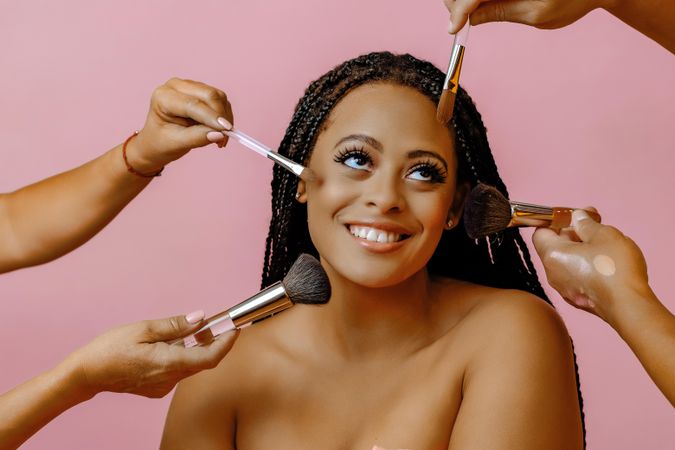 Smiling Black woman with hands doing her make up