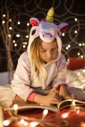Girl reading book in bedroom decorated with Christmas lights