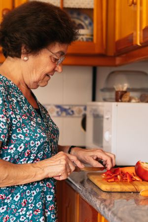 Mature woman cooking with peppers in the kitchen at home