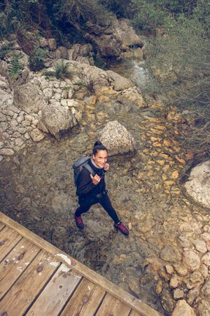 Smiling woman backpacker walking on rocky area with creek