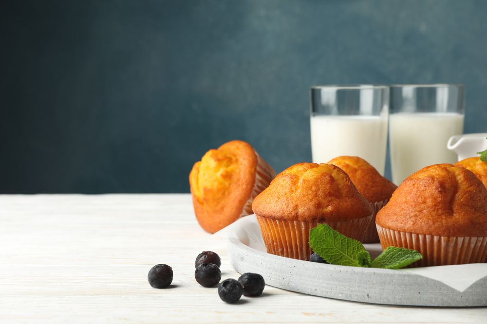Composition with muffins and milk on plain wooden background