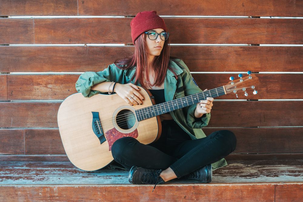 Romantic woman playing guitar leaning on wall