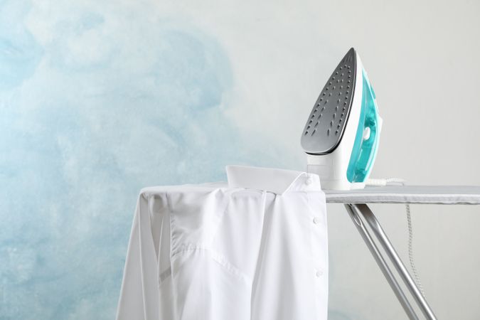 Iron and shirt on ironing board, space for text