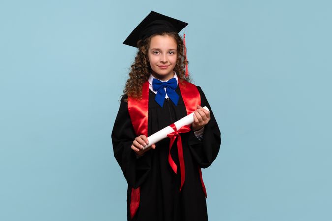 Young girl in graduation attire holding diploma