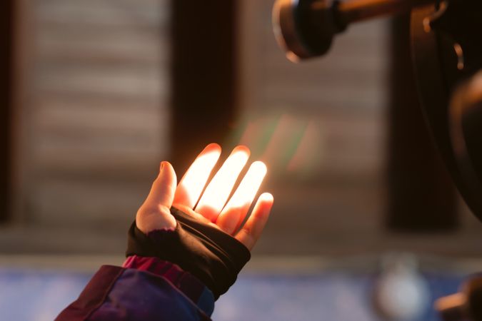 Hand illuminated by telescope light in dark observatory.
