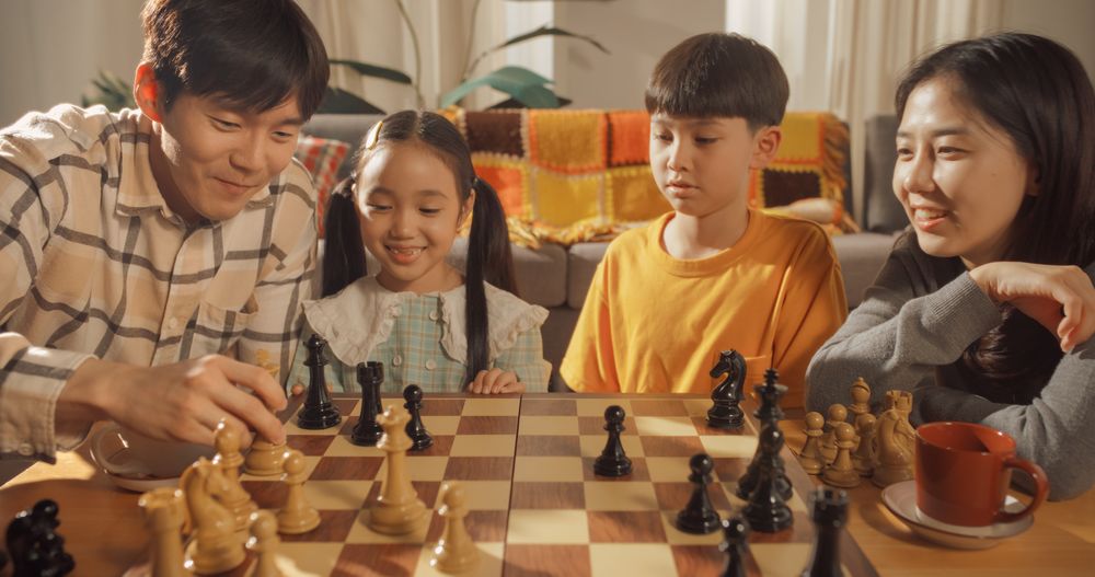 Portrait of a Happy Korean Family Playing Chess in the Living Room.