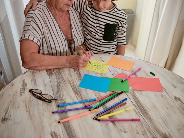 Unrecognizable grandmother and boy drawing on paper