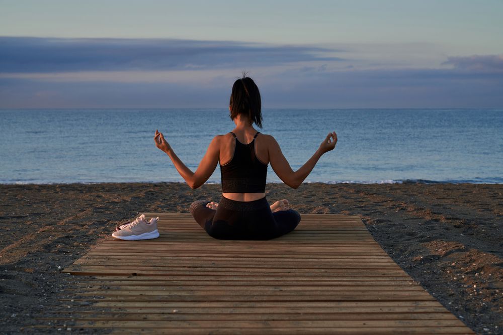 Unrecognizable woman meditating near sea