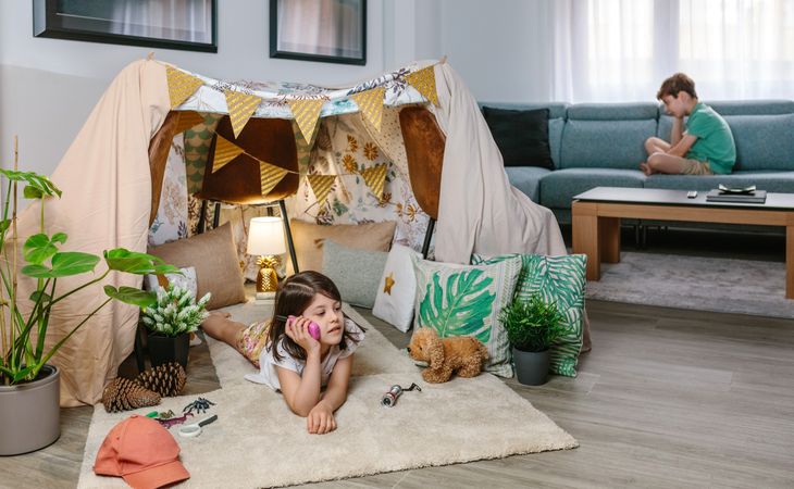 Two happy children talking with walkie-talkie at in cozy tent. Vacation camping at home concept.